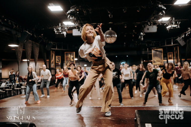 Solo jazz teacher leading a lively dance class, students moving together with energy and joy